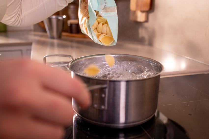 Pasta och vatten i en kastrull på spisen