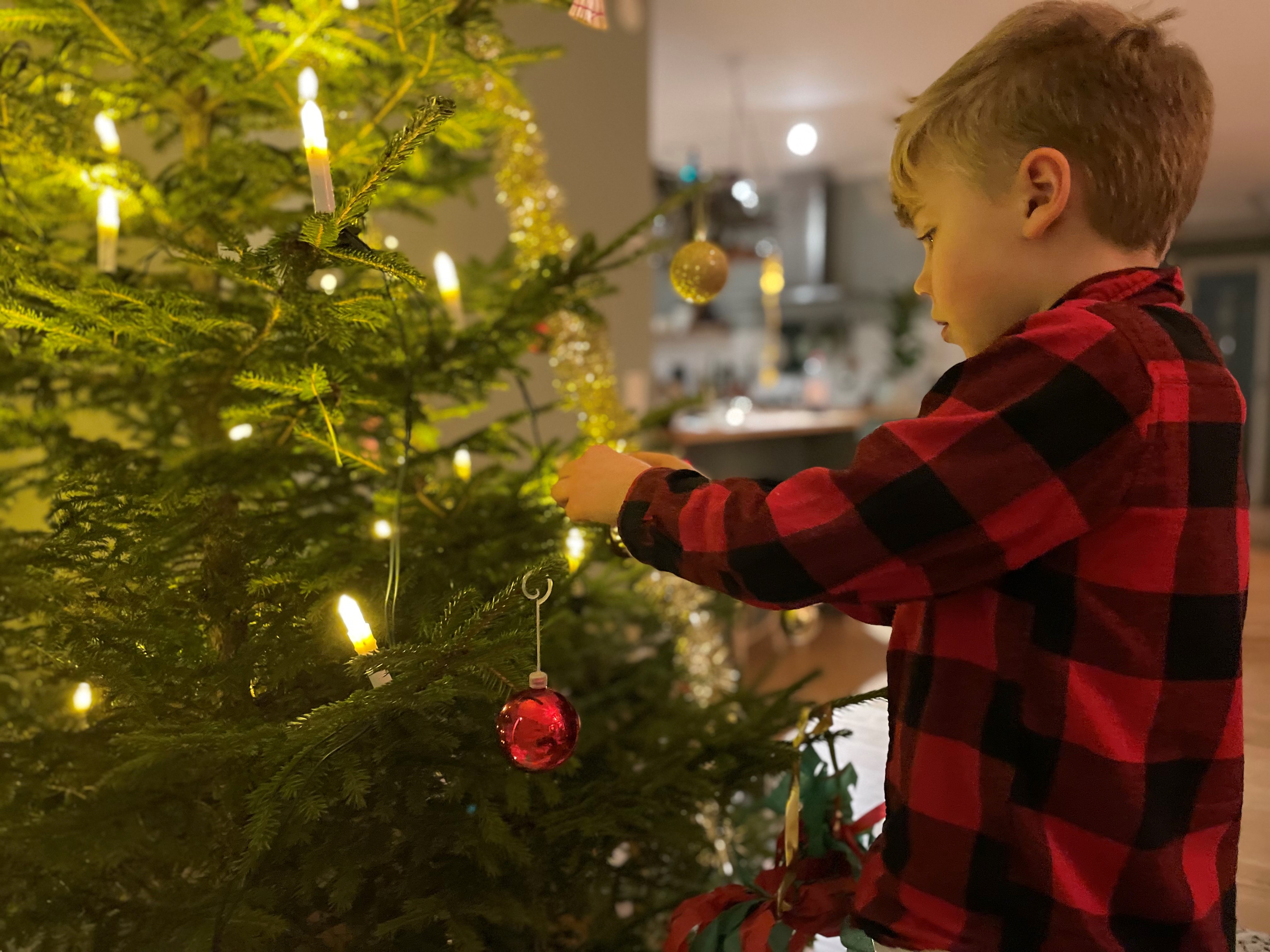 pojke i rutig skjorta hänger upp julgranskula