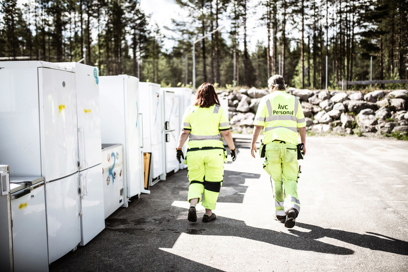 bild på åvcmedarbetare som går förbi en samling av vitvaror på återvinningscentral