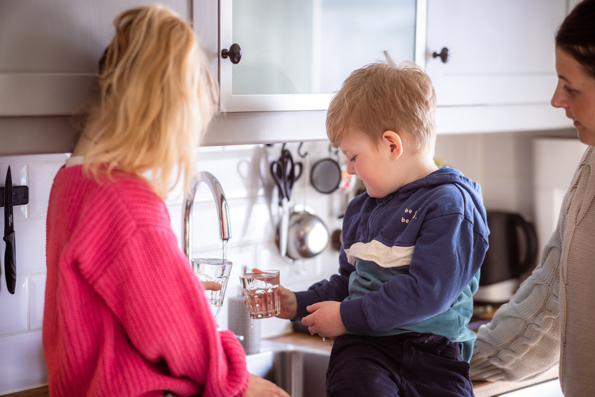 Barn och kvinna häller upp kranvatten i var sitt glas