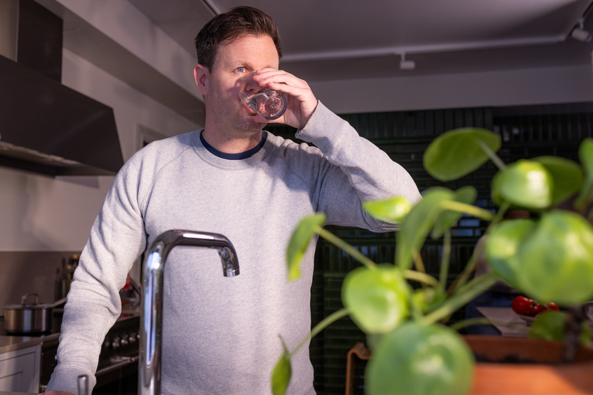 Man som dricker vatten i ett kök