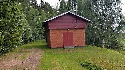 Bild på ett litet rött hus med skog runtom- Överhogdals vattenverk